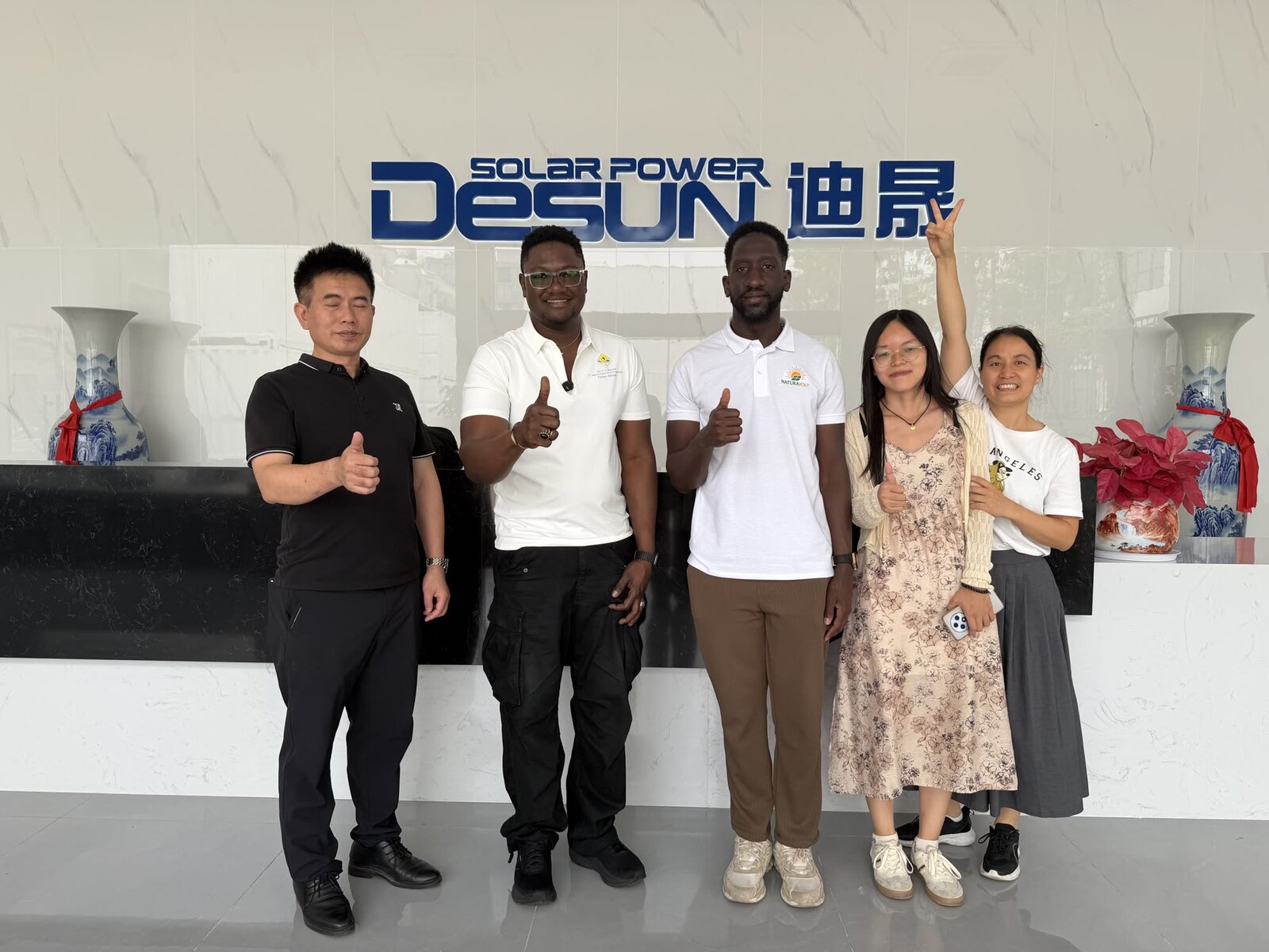 Équipe Full Business World et direction chinoise devant l’enseigne Desun Solar Power